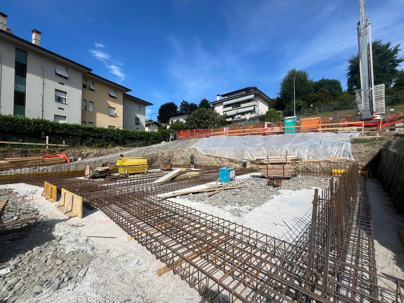 Scavo di cantiere con armature delle fondazioni e gru sullo sfondo