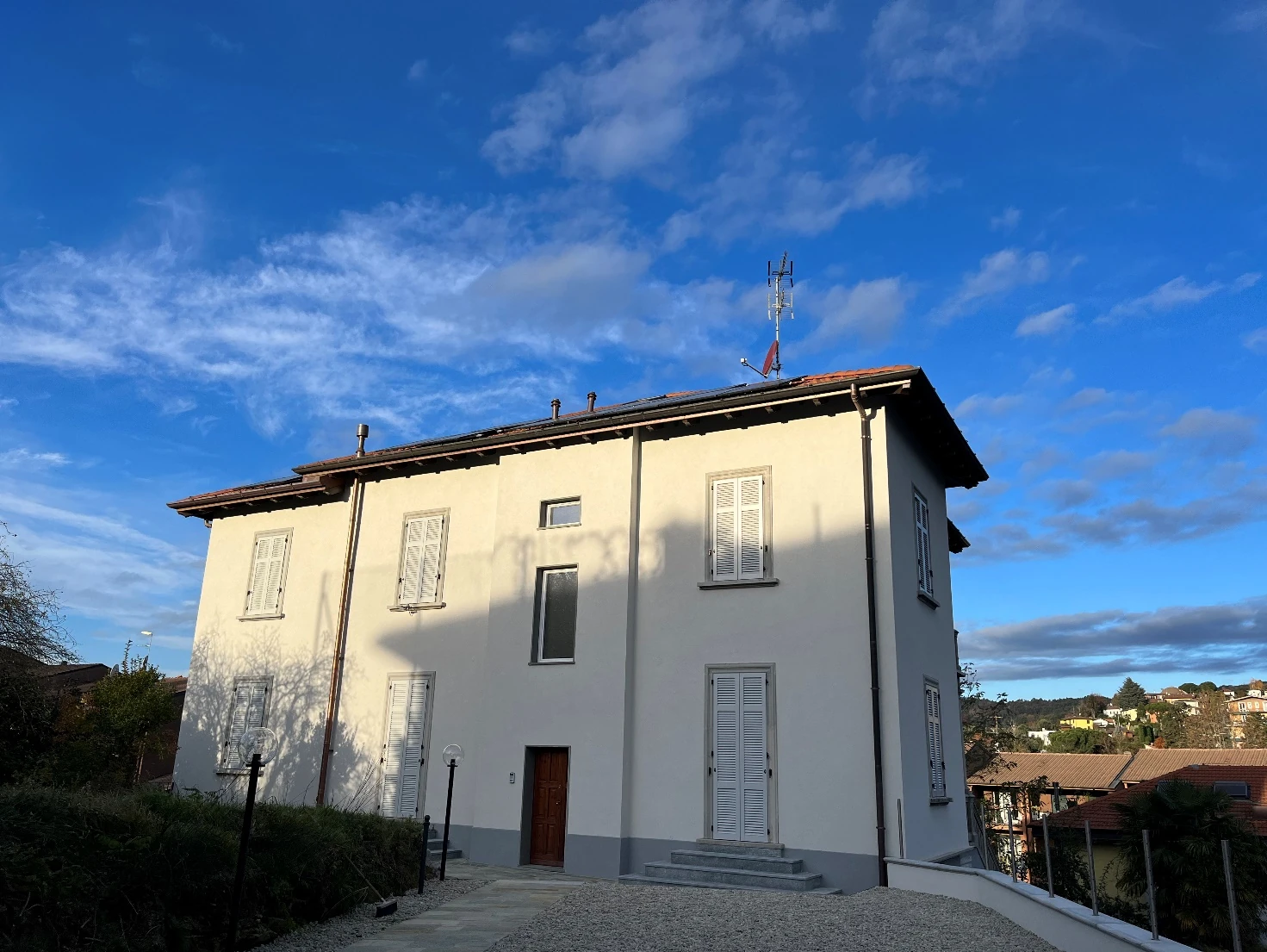 Villa a due piani con facciata chiara, persiane bianche e copertura a falde